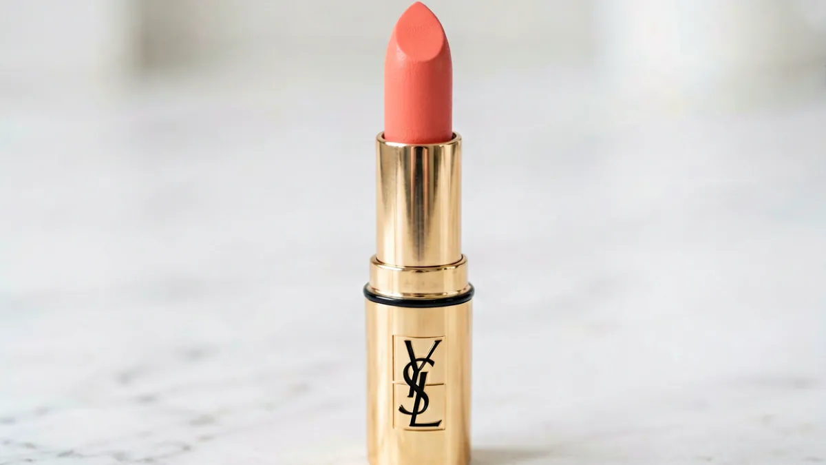 YSL蜜桃色7474口红管身特写，展示其品牌金色Logo与蜜桃橘调色块的产品细节